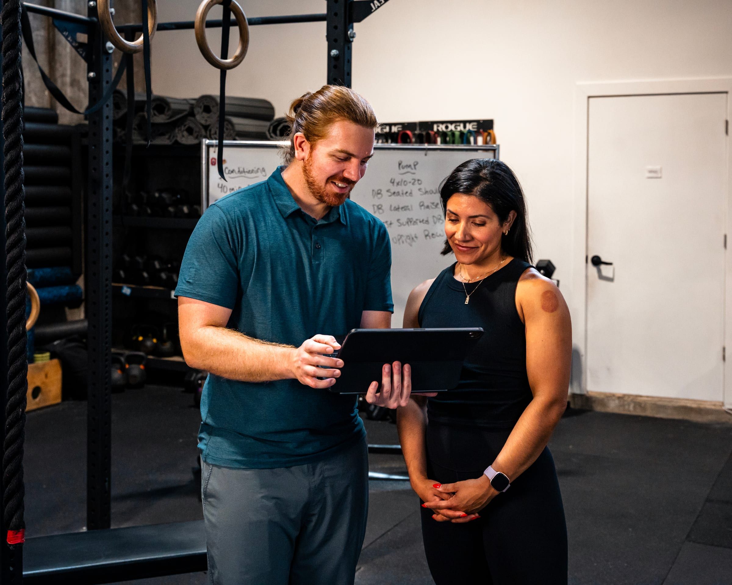 Adam Wilson going over a client’s training plan with her on a tablet